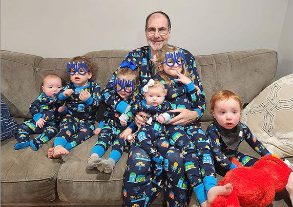 Philip Sherman sits with his six grandchildren during Hanukkah in 2022.